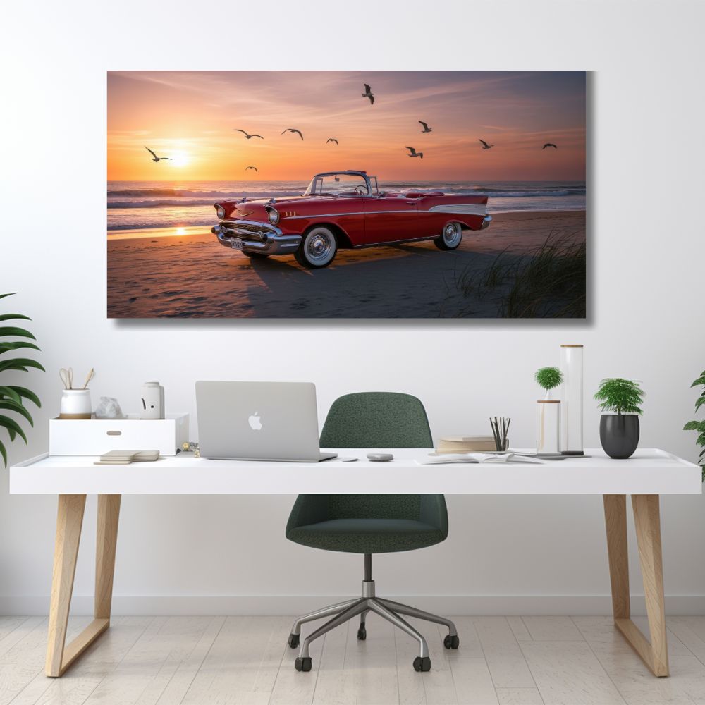 Vodoravna slika crvenog klasičnog automobila na peščanoj plaži tokom zalaska sunca sa galebovima na nebu.